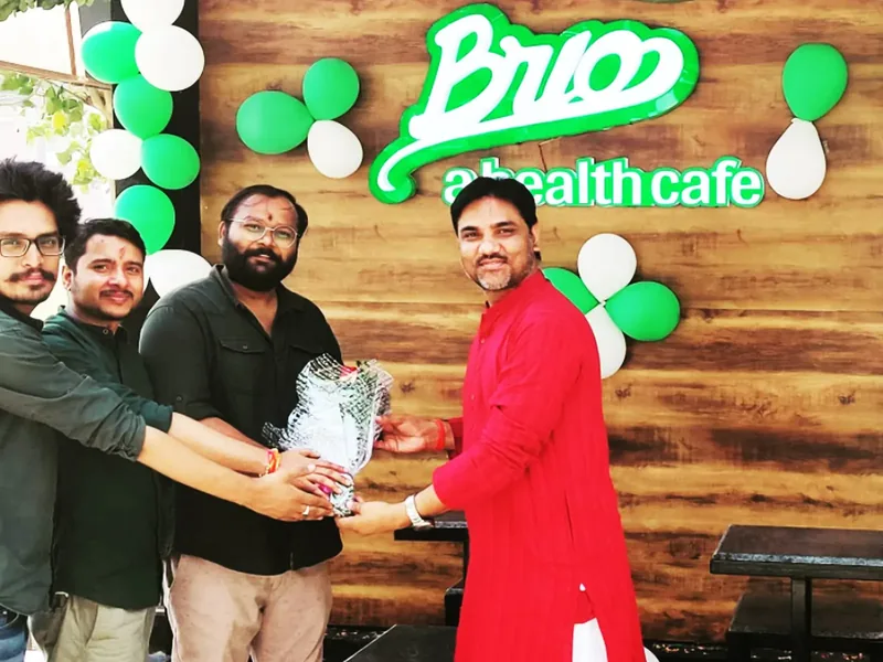 Guests presenting a gift in front of the BRIO sign on a wooden wall